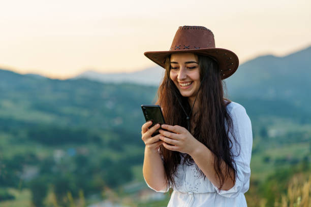 Happy Cow Girl using mobile in mountain for texting
