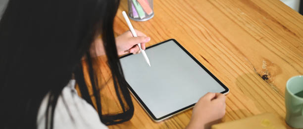 istock A schoolgirl is using a white blank screen computer tablet and stylus pen at the sitting room. 1265033608
