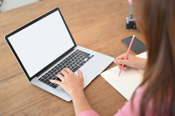 istock A cropped image of a woman is using a white blank screen computer laptop at the wooden table. 1265033728