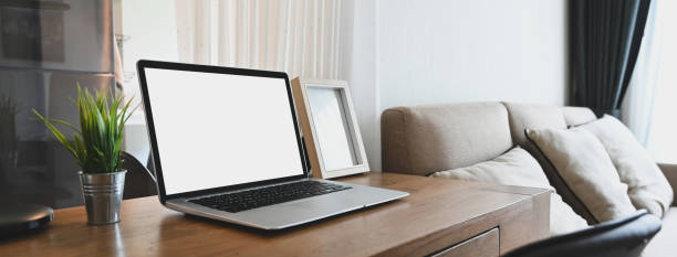 istock A white blank screen computer laptop is putting on a wooden table in a comfortable room. 1265033779