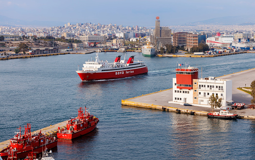 Athens, Greece - April 20, 2011: Ferry and passenger ship passing by tugboats and the Pilot Station at the Piraeus harbor. Commercial and tourist activities is of mayor importance in Greece. Maritime transport is also a main activity due to the large amount of islands in the Greece country.