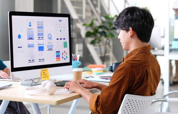 website designer, creative planning phone app development template layout framework wireframe design, user experience concept, young asian man ux designer working on smartphone application at office - designer profissional imagens e fotografias de stock
