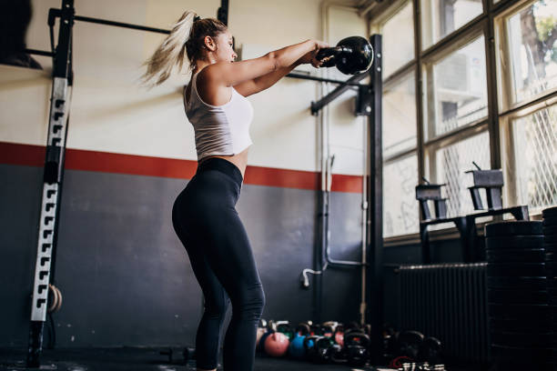 istock Beautiful young woman training with kettlebell in gym 1265039540