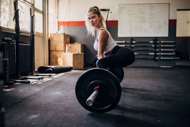 Young woman training with weights in gym One woman, young blonde woman training with weights in gym alone. crossfit girl stock pictures, royalty-free photos & images