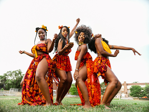 Group of Young African American women dancing together on the field in the park. Public park exterior in the summer.