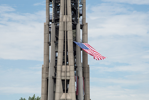 Naperville, Il,United States-April 24,2014: American flag waving in the wind at the top of the Millennium Carillon tower with a blue sky and clouds.