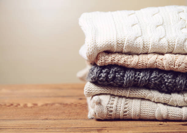 stack of sweaters on a wooden table stack of sweaters on a wooden table sweater stock pictures, royalty-free photos & images