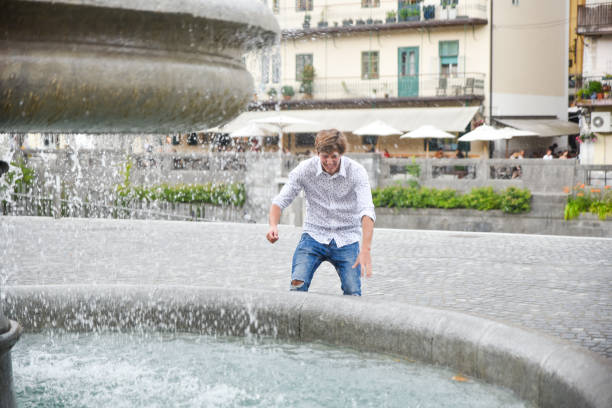 istock Young man playing with water from fountain 1265042075