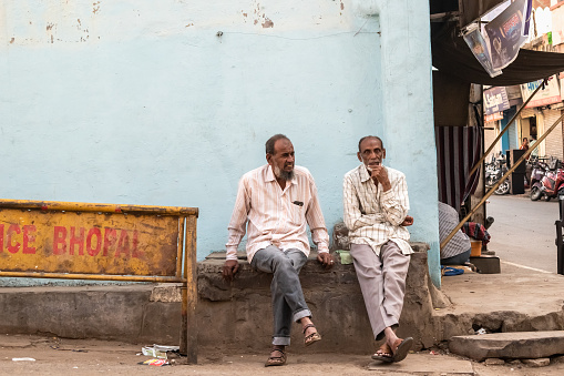 Bhopal, Madhya Pradesh,India - March 2019: Two elderly Indian men sitting on a stone bench on a street in the old city of Bhopal.