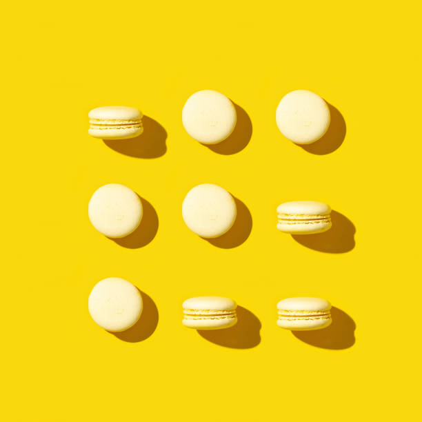 istock Regular creative pattern of bright yellow cookies macarons. Monochrome greeting card 1265044427