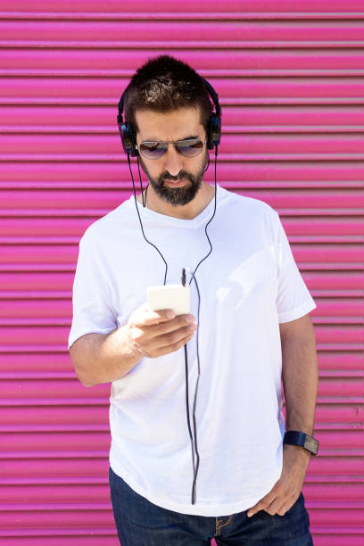 istock Bearded man with headphones and sunglasses using a smartphone while listening music 1265044827
