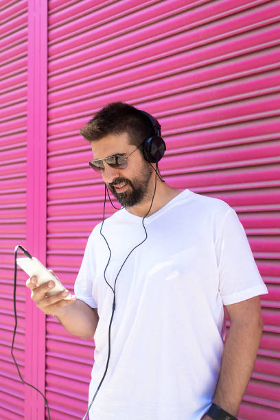 istock Bearded man with headphones and sunglasses using a smartphone while listening music 1265044833