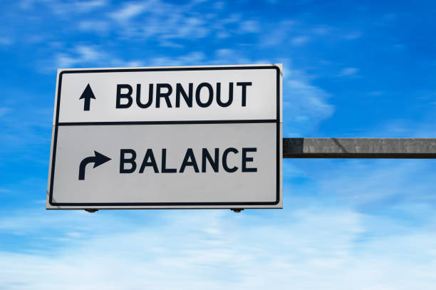 Burnout versus balance. White two street signs with arrow on metal pole. Directional road. Crossroads Road Sign, Two Arrow. Blue sky background. stock photo