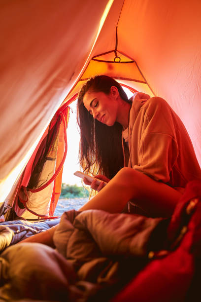 istock Joyful young woman using mobile phone in camp tent 1265049420