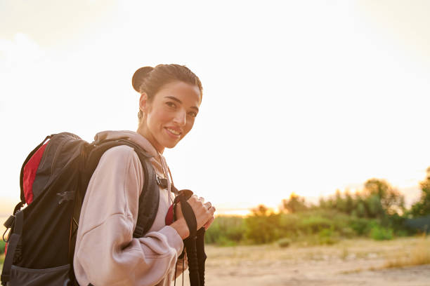 istock Joyful young woman with backpack hiking alone 1265049432