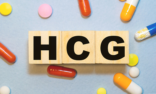 HCG the word on wooden cubes, cubes stand on a reflective white surface, on cubes - a stethoscope. Medicine concept