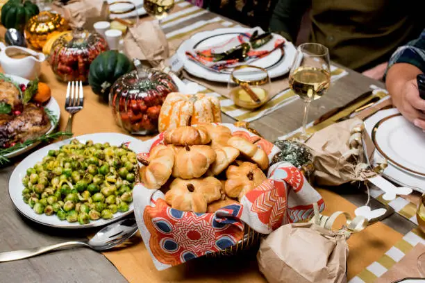 Thanksgiving dinner. Traditional thanksgiving dinner table with stuffed turkey, stuffing, mashed potatoes, green beans, Brussels sprouts, candied yams, ham, dinner rolls, pumpkin pie, pecan pie and red wine. Classic holiday meal.