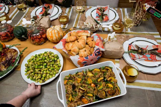 Thanksgiving dinner. Traditional thanksgiving dinner table with stuffed turkey, stuffing, mashed potatoes, green beans, Brussels sprouts, candied yams, ham, dinner rolls, pumpkin pie, pecan pie and red wine. Classic holiday meal.