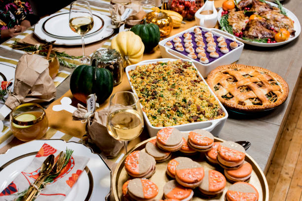 istock Thanksgiving dinner. Traditional thanksgiving dinner table with stuffed turkey, stuffing, mashed potatoes, green beans, Brussels sprouts, candied yams, ham, dinner rolls, pumpkin pie, pecan pie and red wine. Classic holiday meal. 1265050959