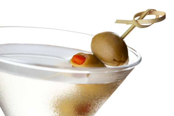 Detail of martini cocktail with vodka, dry gin, vermouth and some olives on a decorative wooden pick isolated on white background