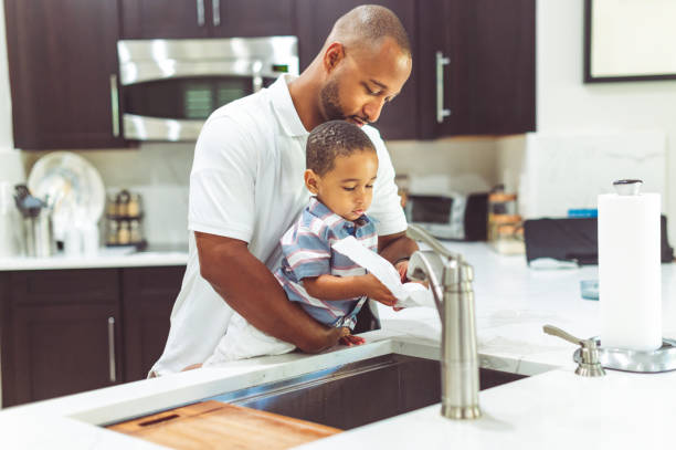 African American father helps his son wash his hands