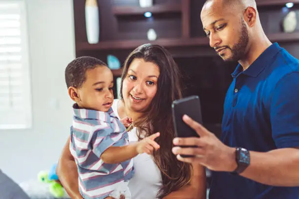 Couple , aunt and uncle to a adorable young child take a selfie with a cell phone camera together at home