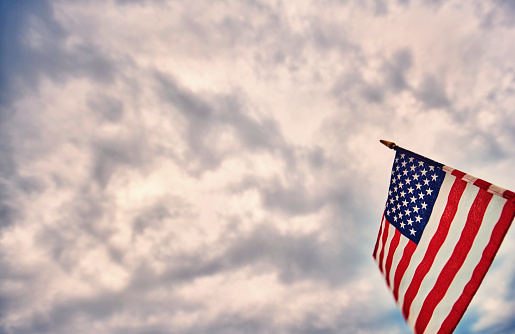 American flags on a flagpole on the blue sky