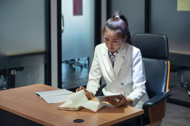 istock Young asian manager woman reading and checking a notebook with tablet on desk in office 1265056768