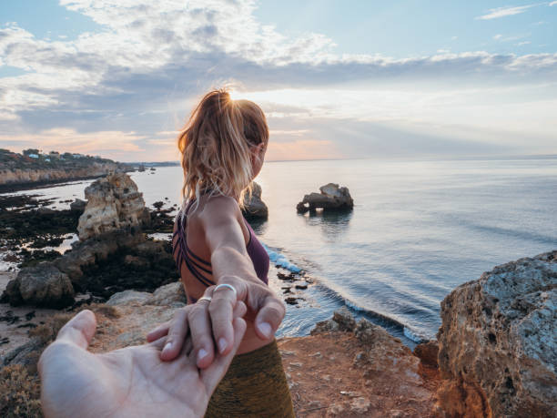 海の上の崖の上で手をつないでいるカップルは、私に従ってください - trust human hand sea of hands holding ストックフォトと画像