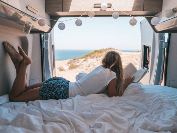 istock Woman lying at the back of a van reading a book 1265067448