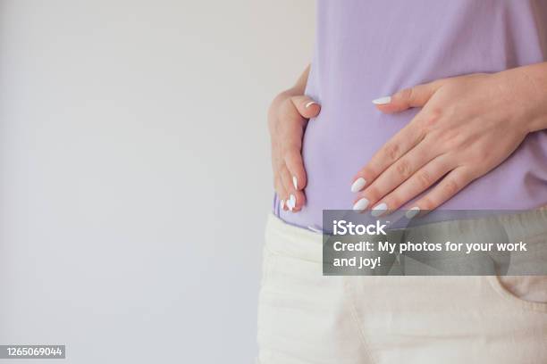 Pregnant Woman In The Early Stages Touches The Belly With Her Hands First And Second Trimester Of Pregnancy Stock Photo - Download Image Now