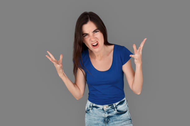 istock Young girl studio standing isolated on grey hands aside emotional looking camera angry 1265071856