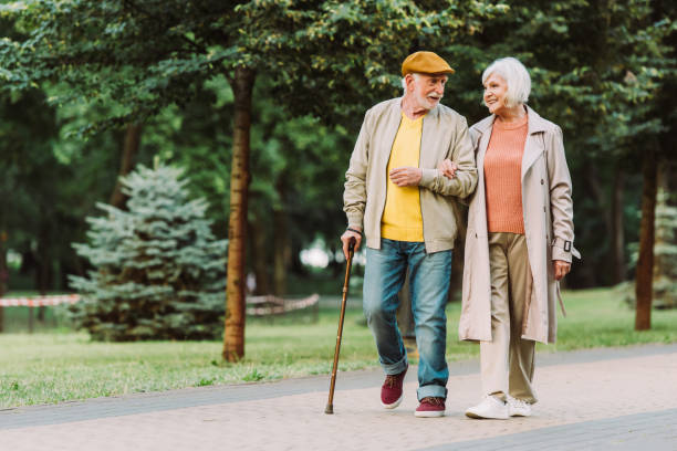 Senior couple smiling while walking on path in park stock photo
