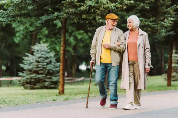 Photo of Senior couple smiling while walking on path in park