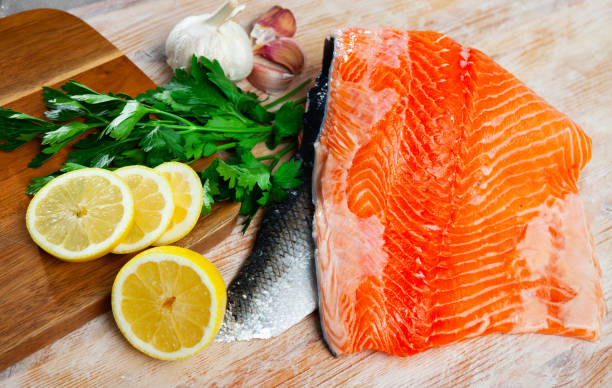 istock Appetizing raw salmon fillet with lemon and greens 1265075872