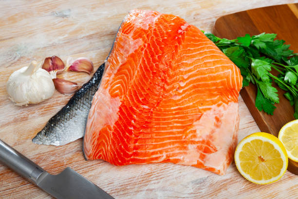 istock Uncooked fillet salmon fish with parsley and garlic on table 1265075878