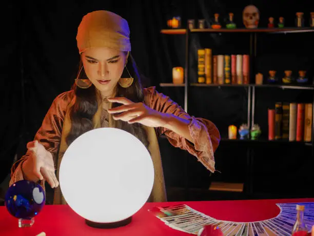 Asian woman fortune teller using divine magical power crystal ball to forecast psyshic future luck
