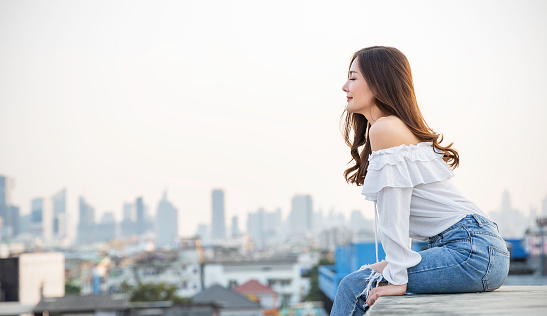 Portrait of young beautiful asian woman sitting in sky fresh air roof top. Smile face asian girl wear casual. Beauty treatment perfect clear skin japanese makeup asia woman lifestyle concept