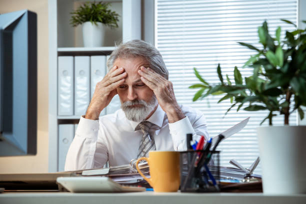istock Tired businessman working late from home holding his head 1265078781