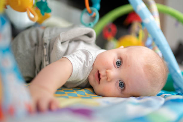 istock Cute baby playing on playmat with hanging mobile 1265079974