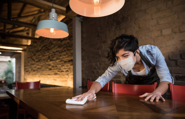 istock Waitress at a restaurant wearing a facemask and cleaning the tables 1265081944