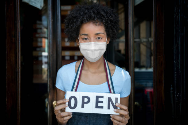 istock Waitress wearing a facemask and holding open sign at a restaurant 1265081973