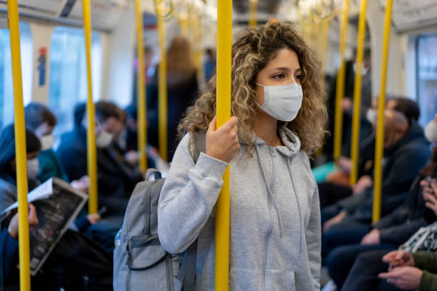 donna in sella alla metropolitana che indossa una maschera facciale per evitare una malattia infettiva - london underground foto e immagini stock