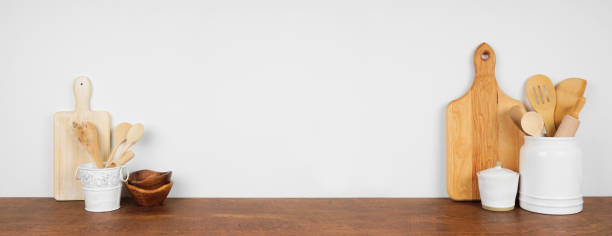 istock Kitchenware and utensils on a wood shelf or counter. Banner with copy space against a white wall. 1265082085