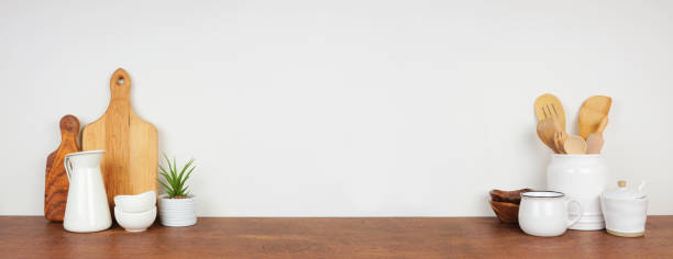 istock Kitchenware and utensils on a wood shelf or countertop. Banner with a white wall background and copy space. 1265082159