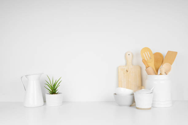 Kitchenware and utensils on a white shelf or countertop with a white wall background and copy space