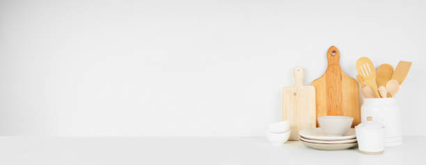 istock Kitchenware and utensils on a white shelf or counter. Banner with a white wall background and copy space. 1265082215