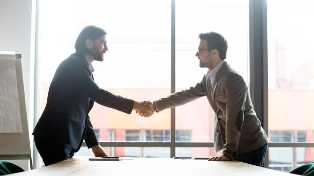 istock Smiling male partners handshake greeting at meeting 1265084525