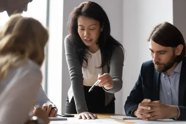 Photo of Confident Asian businesswoman talk with diverse colleagues at meeting