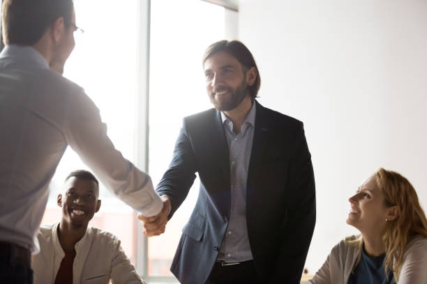 istock Smiling businessmen shake hands closing deal at briefing 1265084561
